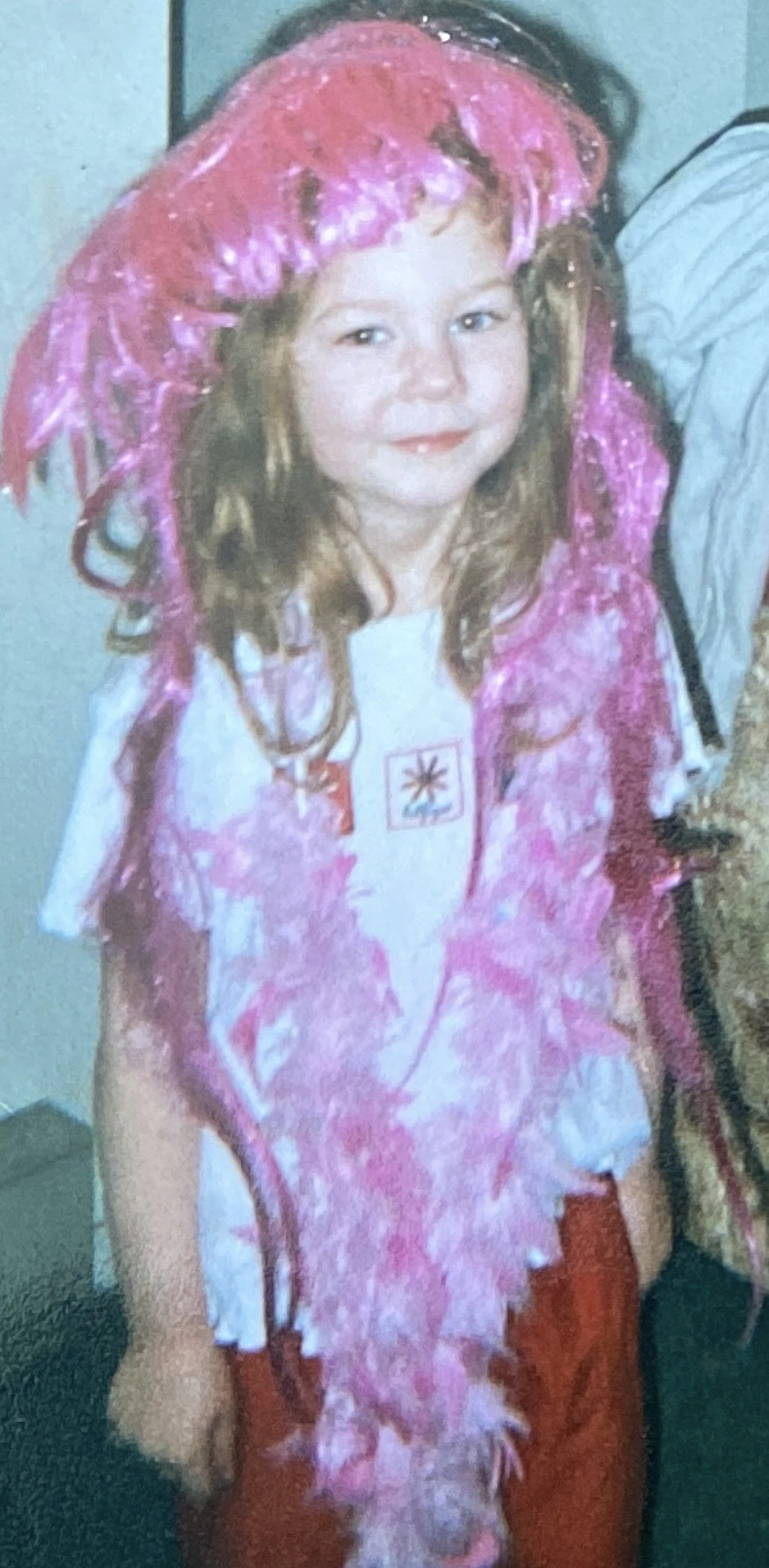 A little girl wearing a pink hat and holding a teddy bear.